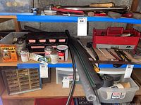 Full view of shelving unit with plumbing chemicals, tools, adhesives, organized hardware, clamps, hand tools, and toolboxes.