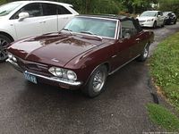 Front and driver side three-quarter view showing burgundy exterior, black soft top, chrome bumpers, Cragar wheels, license plate