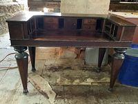 Front view of the antique spinet desk showing small drawers, cubbies, and tapered legs.