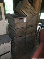 Stack of 11 old wooden apple crates showing weathered wood and cut-out handles.