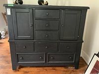 front view of painted wood Pottery Barn armoire dresser showing two side cupboards with doors, three small top center drawers, three mid-size middle drawers and two large bottom drawers