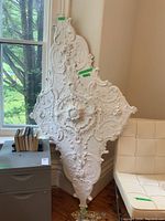 Full view of the large white ornate ceiling molding panel leaning against wall and window, showing overall condition and size.