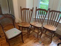 Three solid wood chairs with spindled backrests and turned legs next to one parlour chair with fabric seat cushion, all placed on a wooden floor.
