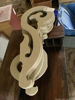 Six light green painted wood corbels stacked with visible scroll detail, minor wear visible on edges.