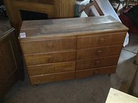 Front view of vintage wood dresser showing eight drawers with wooden block handles, clear wear and scratches on surface.