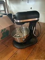 Front-three-quarter view of mixer mounted on base with bowl and attachments inside