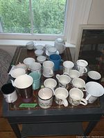 Full set of mugs, tea set pieces, and wreaths arranged on a table by a window.
