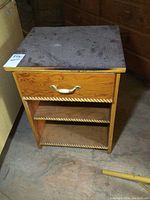 Front view of vintage wooden nightstand showing one drawer with a gold-toned handle and two shelves with decorative trim.