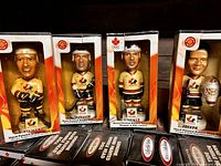 Four hand painted Team Canada hockey player bobble heads in original boxes showing detailed hockey uniforms and player faces with names at base visible.