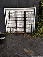 Two iron fencing panels leaning against a white garage door, showing overall design and condition