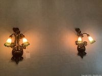 Pair of wall sconces mounted on wall, both lit