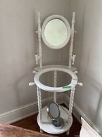 Full view of white painted wood washstand with oval mirror on top and small round mirror on lower shelf