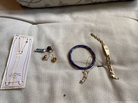 Overview of necklace, earrings, blue bangle, and gold bracelet