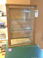 Front view of the wood framed glass display case with two glass shelves inside.