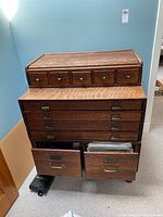 Front view showing top small drawers, lower file drawers with one open, visible hanging files.