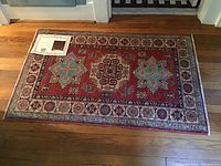 Full view of the rug laid on hardwood floor with certificate of authenticity on top corner