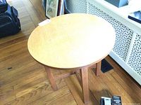 Overall view of round wooden table with four-leg cross-stretcher base