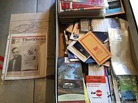 Overview of train maps, timetables, and related papers, some in protective sleeves, and stacked newspaper pages