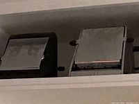 Two vintage chrome toasters positioned side by side on a shelf, showing boxy designs, one more squared, the other rounded edges with black levers.