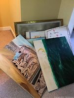 Group shot of all artworks and two metal frames leaning against wall