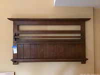 Front view of oak wall shelf showing slatted back panel and two horizontal rails