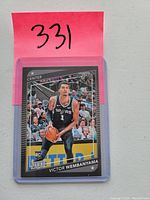 Front side of the Victor Wembanyama rookie card showing player in Spurs uniform with Panini logos and rookie card indicator
