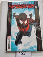 Comic book in protective sleeve showing cover art of Ultimate Comics Spider-Man #1 with Spider-Man in black and red suit.