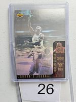 Front of Michael Jordan Upper Deck hologram basketball card. Shows Jordan in Bulls uniform making a basketball shot with hologram effect, card protected in plastic sleeve with lot number 26.
