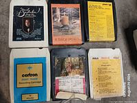Six 8-track tapes shown with identifiable labels including Neil Sedaka, Dreamer by Candlelight, Certron brand, and RCA tapes with program listings.