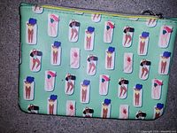 Small clutch bag with a light green background featuring a swimsuit pattern in glasses, showing zipper closure