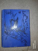 Front cover of the blue hardcover book titled 'Book of Fables' with black embossed bird illustration.
