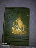 Front cover showing green cloth binding with gilt-stamped rabbit illustration and bamboo motif