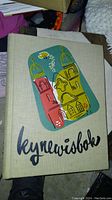 Front cover of the yearbook featuring colorful building illustrations with birds and the title 'keynevisbok'.