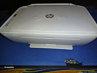 Front and top view of HP all-in-one printer showing scanner lid and HP logo