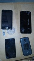 Image showing three smartphones, one LG with screen intact, one cracked screen phone, one with damaged back cover