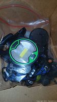 View of flashlights and headlamp components in box, showing black and green LED headlamp and various parts