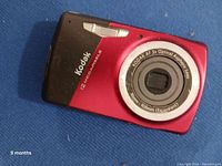 Front view of Kodak digital camera showing red and black body, lens, and markings