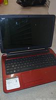 Front view of the HP Notebook 15-f272wm laptop with screen and keyboard, showing red base and black keyboard.