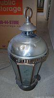 Full view of hexagonal metal lantern showing metal wear and glass panels, with storage box background