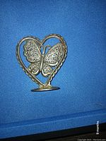 Front view of silver plated butterfly and heart-shaped earring holder with multiple holes for earrings