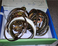 Top-down view of assorted metal and enamel bracelets and bangles in an open box