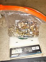 Jewelry lot weighed on Pelouze scale showing 14.1 ounces.