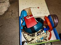 Various bangles and chain necklaces in a box, showing colors including blue, red, orange, purple, and pearl-like beads.