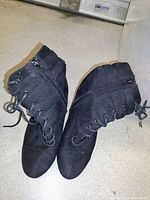Pair of black lace-up ankle boots with side zipper, made of suede-like material, showing some wear.