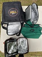 Four insulated lunch bags laid out on table showing exterior and open insulated interiors