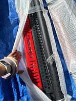 Partially unwrapped OEDRO branded running board with visible red metal branding plate and textured step surface.