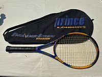 Full view of Prince Longbody Thunder Extreme Titanium tennis racket alongside its branded cover laid on a flat surface.