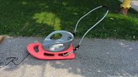Side view of red Flexible Flyer snow stroller sled with gray cushioned folding push handle, showing the runners and body design.