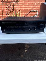 Front view of Yamaha RX-V660 showing buttons, knobs and display panel in outdoor light against brick background