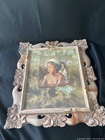 Full view of framed artwork featuring a portrait of a Balinese woman with a bird, with ornate carved wood frame.